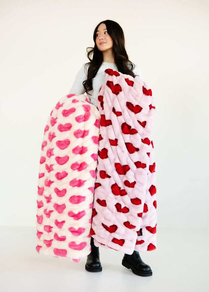 A model holding Minky Hugs Heart Pink and Red Blankets, showcasing festive design for Valentine's Day.
