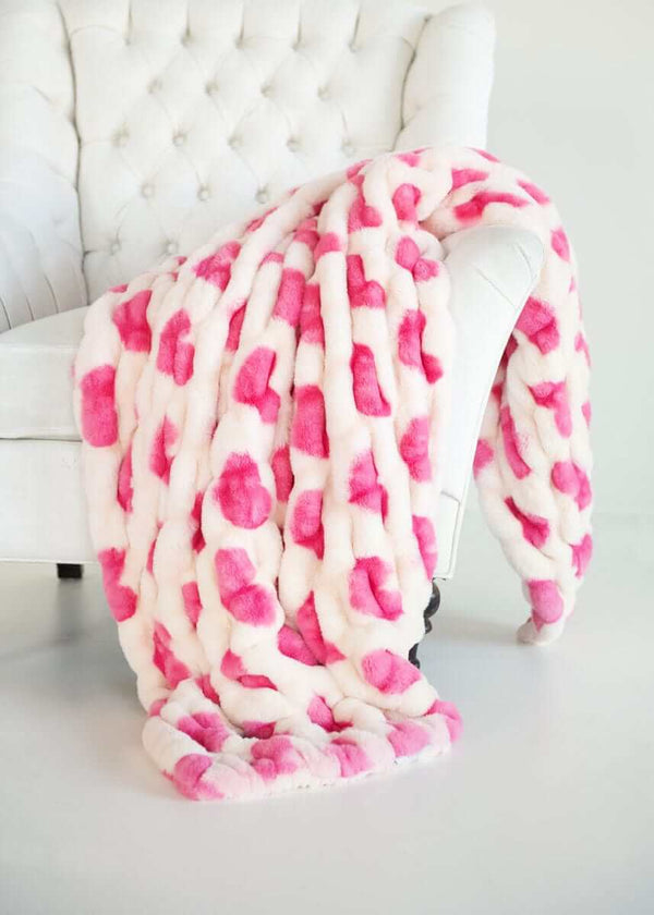 Hugs Heart Pink Blanket draped over a white chair, featuring pink hearts for a cozy Valentine's touch.