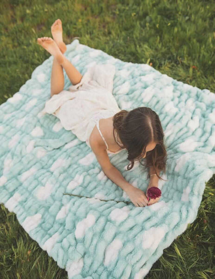 Child relaxing on the Minky Couture Hugs Polka Dot Tiffany Blanket with cream polka dots.