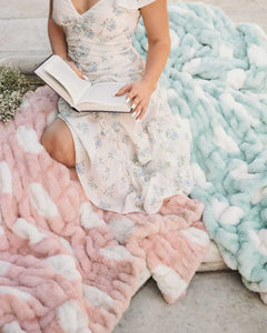 Model sitting with Minky Couture Hugs Polka Dot Blush plush blanket, reading a book on a soft, cozy, colorful blanket.
