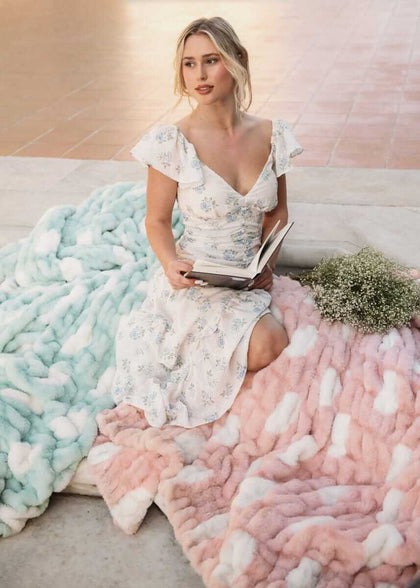 Model reading a book with Hugs Polka Dot Tiffany Blanket in Tiffany blue and a pink blanket on the floor.