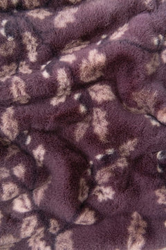Close-up of a plush faux fur fabric with a mottled pattern in dark purple and light beige.