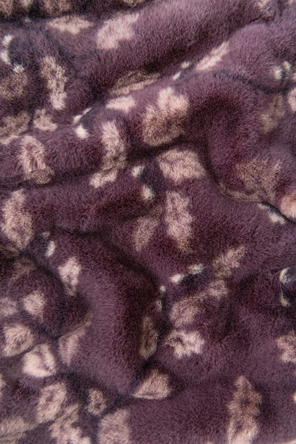 Close-up of a plush faux fur fabric with a mottled pattern in dark purple and light beige.