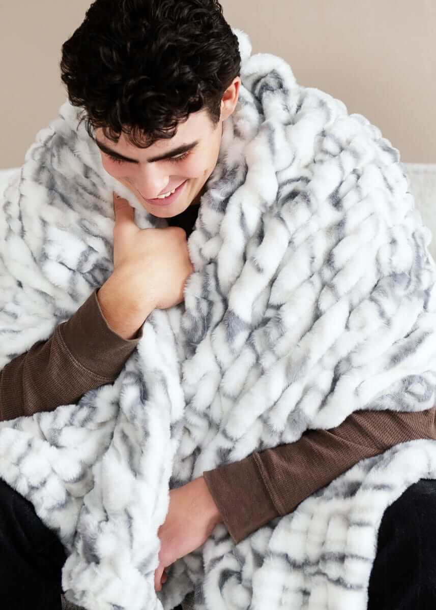 Hugs Marble Pewter Blanket draped over a smiling person, showcasing its plush and cozy design.