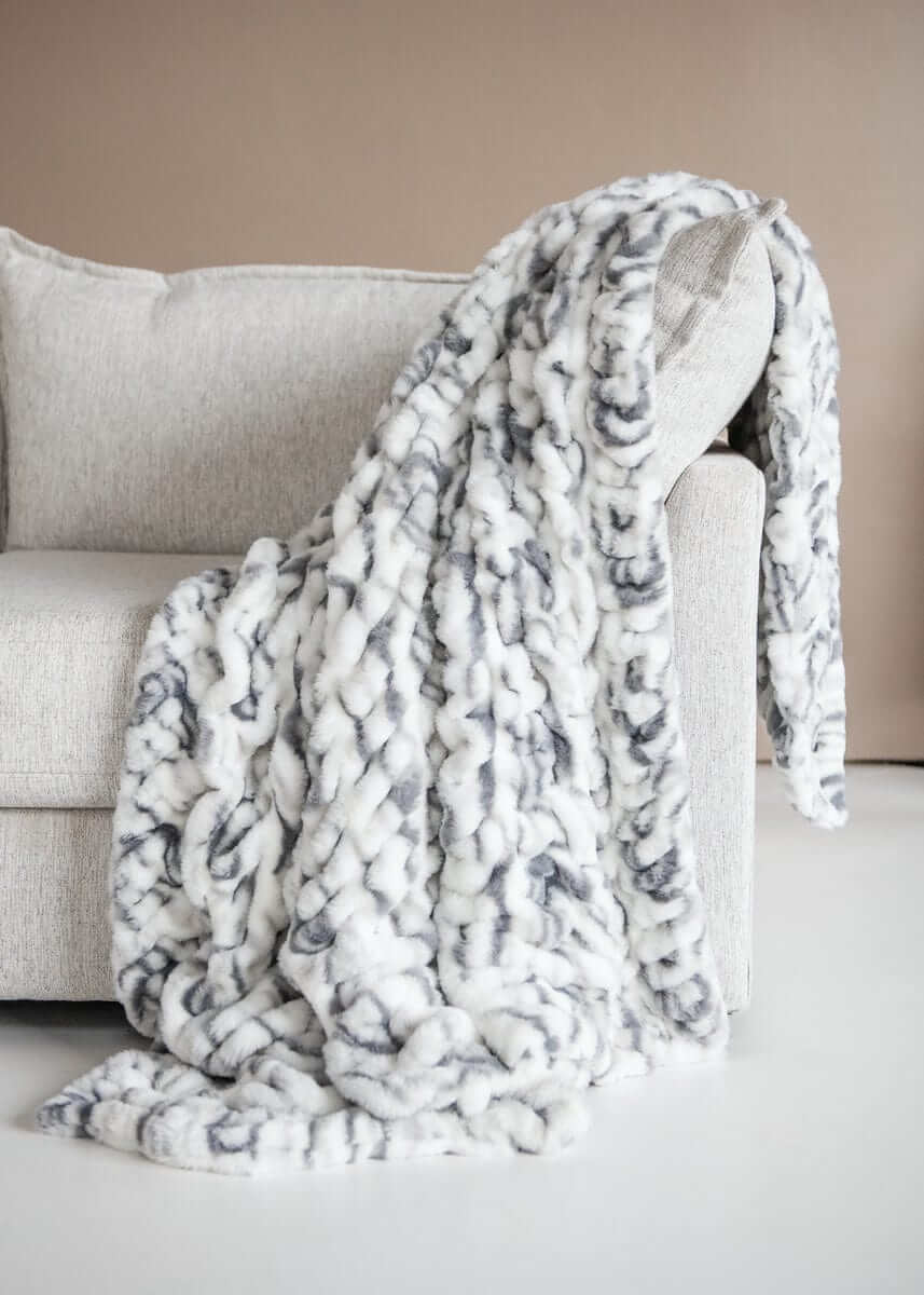 Hugs Marble Pewter Blanket draped over a cozy couch, showcasing modern elegance with a plush marble design.