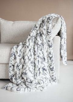 Hugs Marble Pewter Blanket draped over a cozy couch, showcasing modern elegance with a plush marble design.