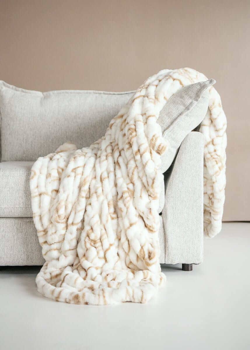 Hugs Marble Sand weighted blanket draped over a couch, showcasing its cozy tan marble design and plush texture.