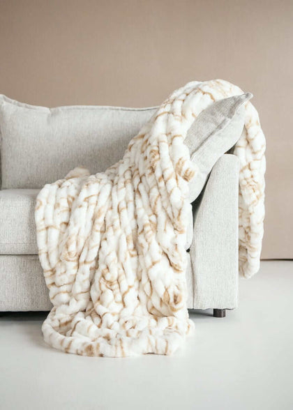 Hugs Marble Sand weighted blanket draped over a couch, showcasing its cozy tan marble design and plush texture.