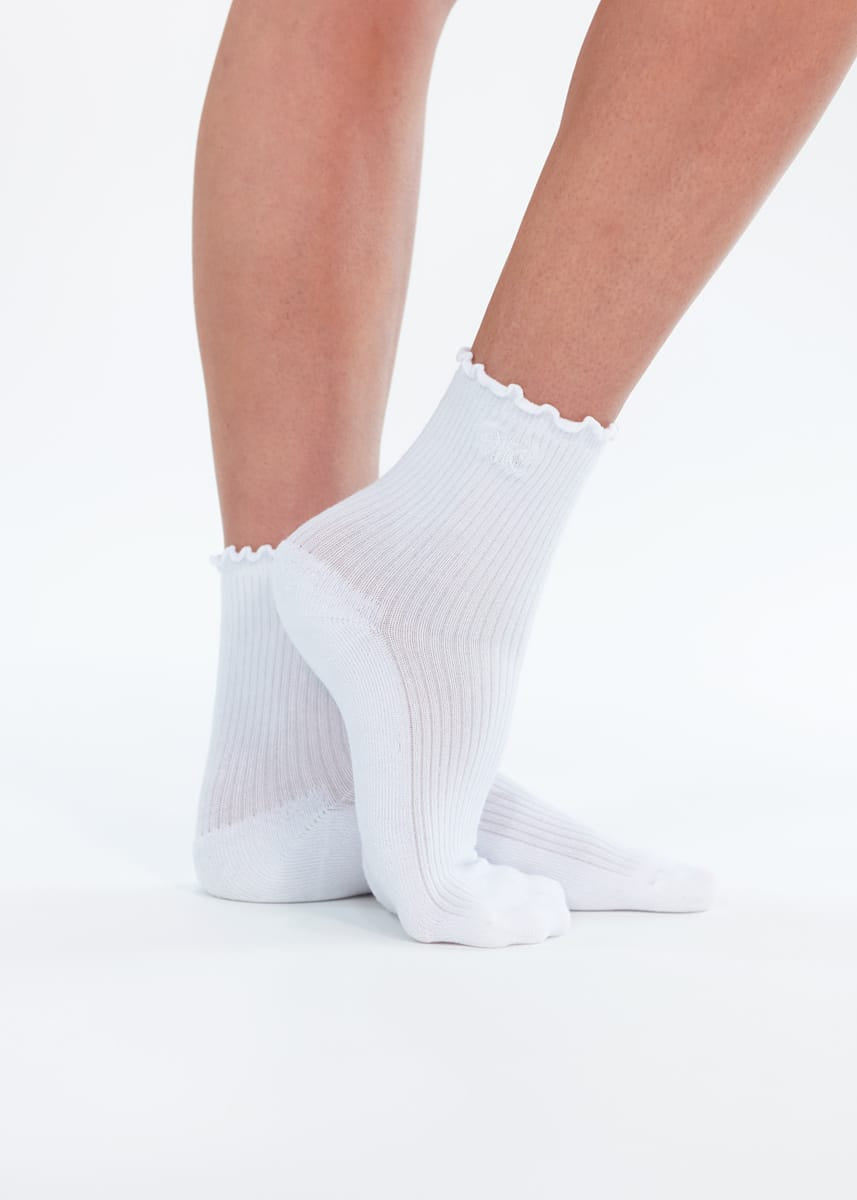 White ankle socks with a scalloped edge, shown on a person's feet against a clean white background.