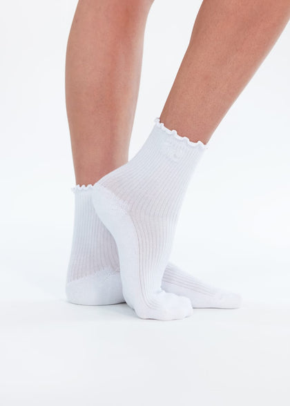 White ankle socks with a scalloped edge, shown on a person's feet against a clean white background.