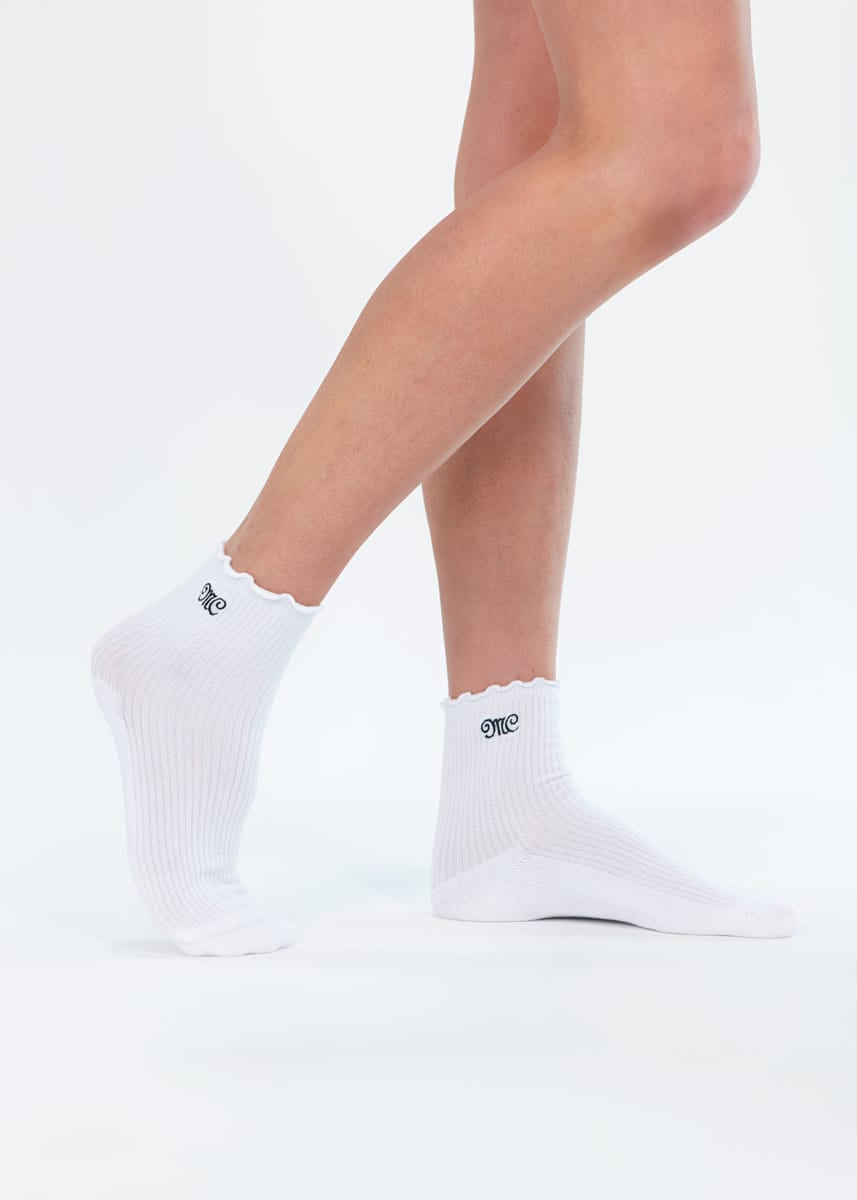 White ankle socks with scalloped edges worn on a model's feet, shown against a seamless white background.