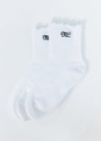 A pair of white ribbed ankle socks with scalloped edges and black embroidered MC Minky Couture lettering on the cuffs, displayed on a clean white background.