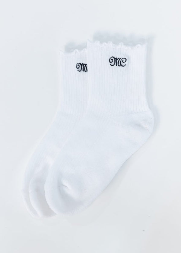 A pair of white ribbed ankle socks with scalloped edges and black embroidered MC Minky Couture lettering on the cuffs, displayed on a clean white background.