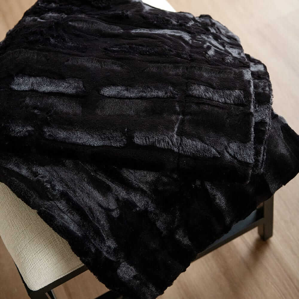 Close-up of a black Minky Couture plush blanket draped over a bench.