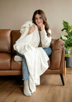Woman holding a cream Minky Couture blanket, enjoying a soft and cozy indoor moment.