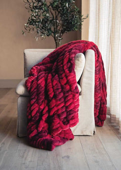 Hugs Diamond Red patterned blanket draped over a beige armchair in a room with a plant and window.