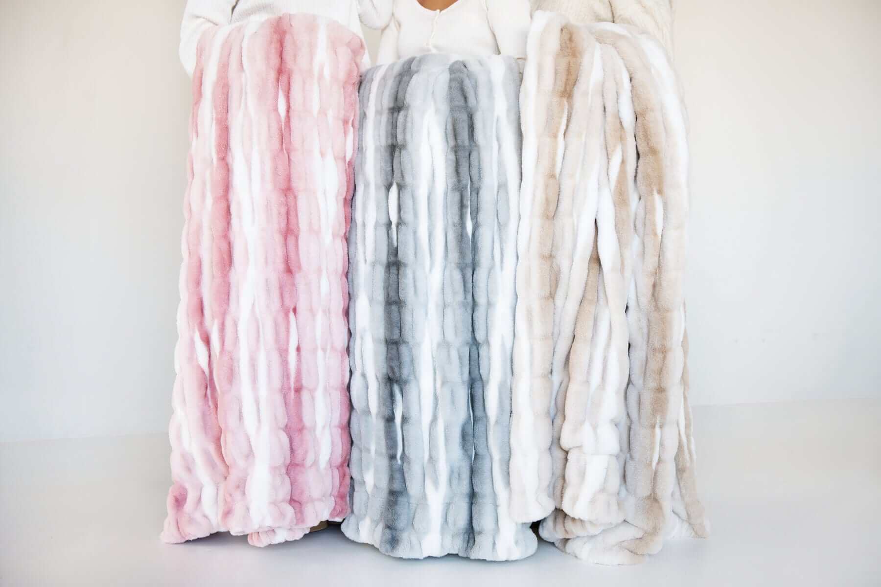 Minky Couture Hugs Swirl Blanket displayed in pink, gray, and caramel variants for cozy home decor.