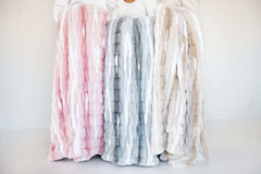Minky Couture Hugs Swirl Blanket displayed in pink, gray, and caramel variants for cozy home decor.