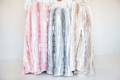 Minky Couture Hugs Swirl Blanket displayed in pink, gray, and caramel variants for cozy home decor.