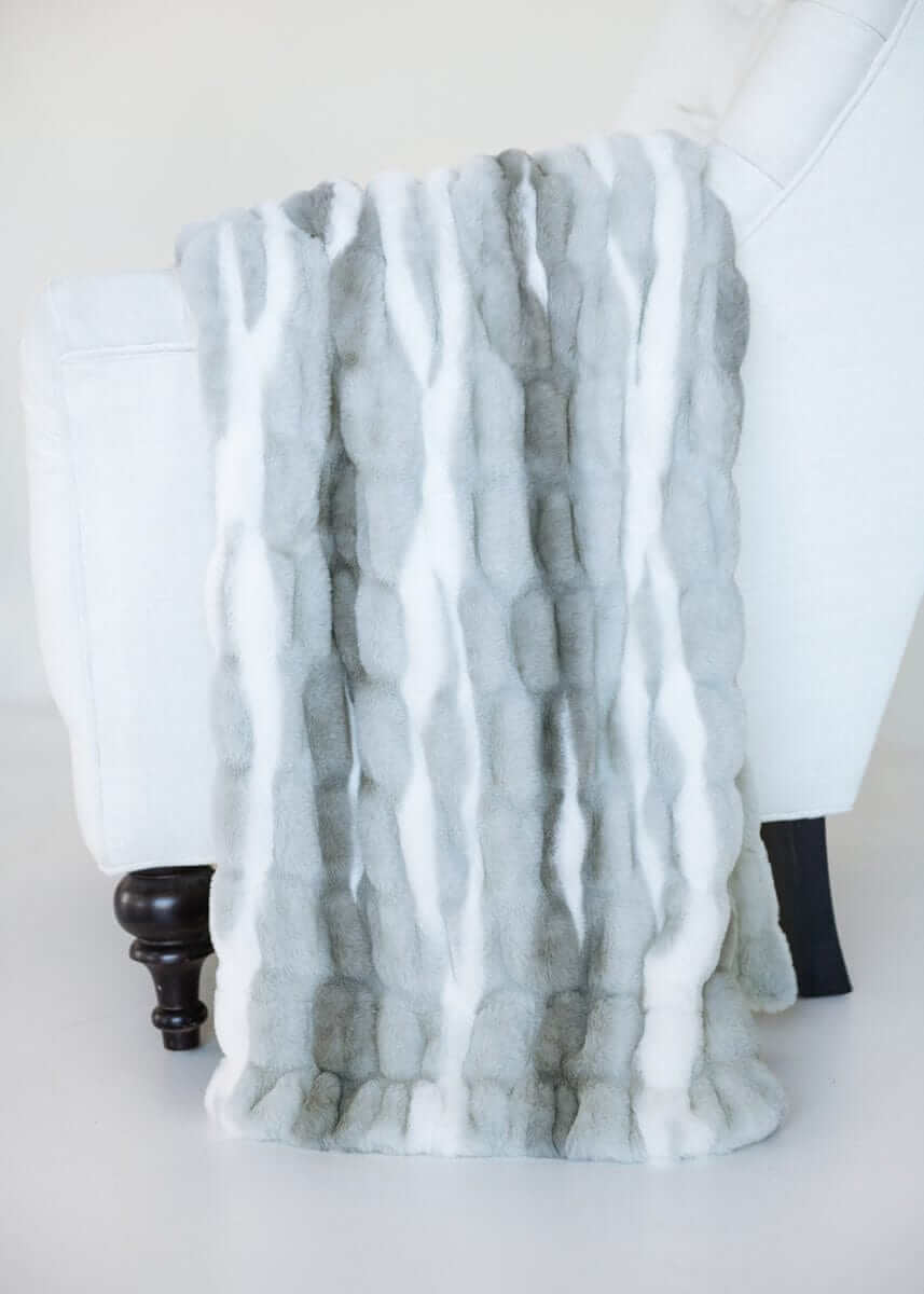 Cozy White Glove Hugs Swirl Licorice throw blanket displayed on a chair, showcasing its luxurious material.