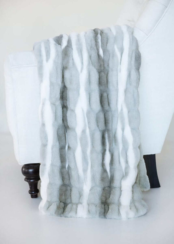 Cozy White Glove Hugs Swirl Licorice throw blanket displayed on a chair, showcasing its luxurious material.