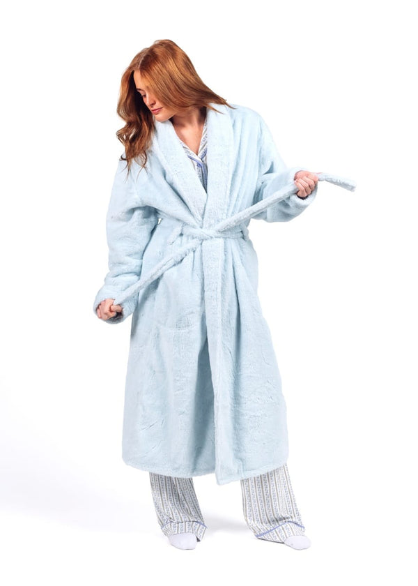 A woman wearing a light blue plush bathrobe with a tie belt and matching striped pajama pants, standing against a plain white background.