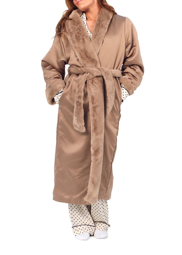 A woman wearing a long taupe-brown plush faux fur robe with a matching tie belt, paired with white and black polka dot pajama pants and white socks, against a plain white background.