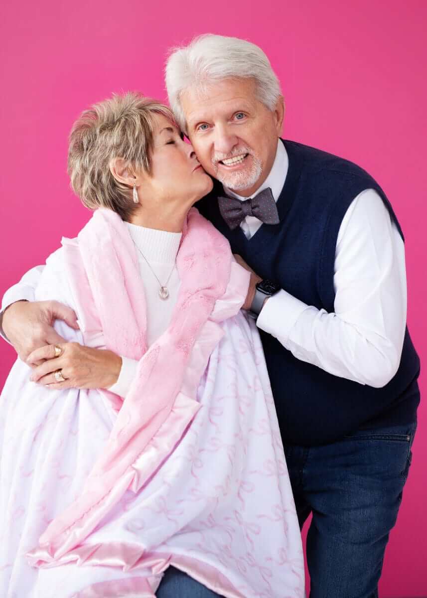 Couple enjoying a cozy moment with a blanket featuring Pink Ribbon Bows on a pink background.