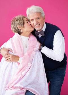 Couple enjoying a cozy moment with a blanket featuring Pink Ribbon Bows on a pink background.