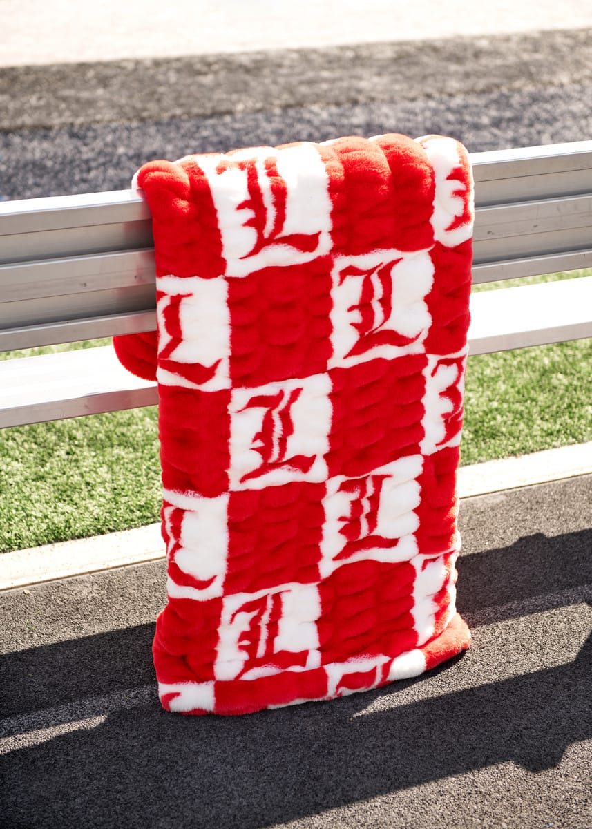 University of Louisville Blanket hanging on a bench, featuring red and white checkered design with logos.