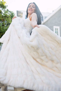 Woman holding a cream Minky Couture weighted blanket outdoors, oversized drape and ultra-soft texture.