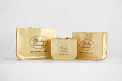 Minky Couture reusable shopping bags in gold, perfect for groceries and gifts, featuring large, medium, and small sizes.