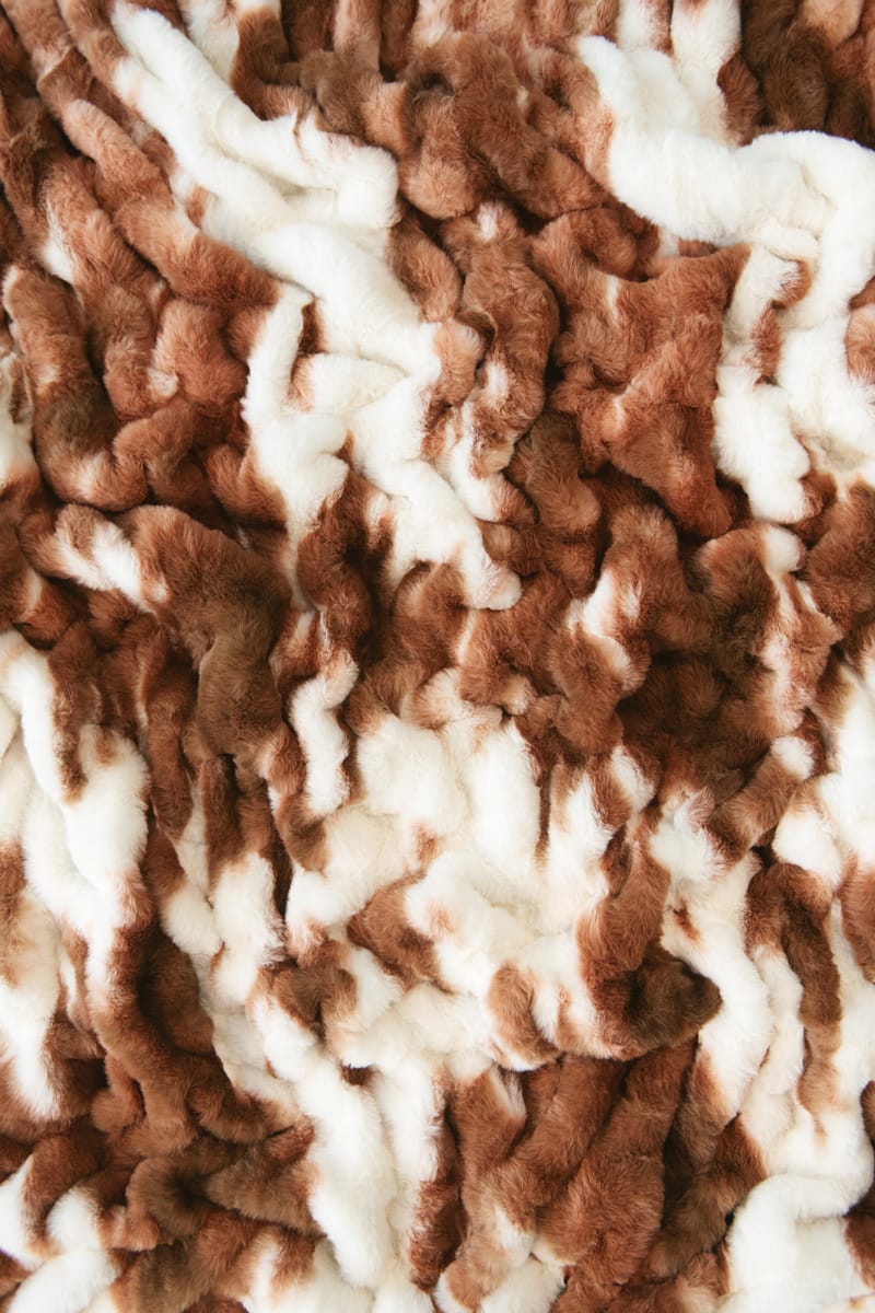A close-up of a plush minky fabric with a brown and white cow hide pattern.
