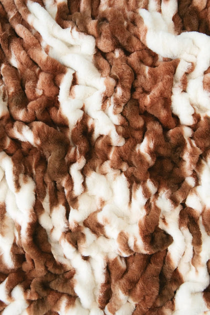 A close-up of a plush minky fabric with a brown and white cow hide pattern.