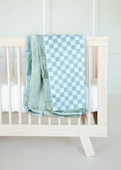 Minky Couture blue and white Checkered Cactus baby blanket draped over a light wood crib.