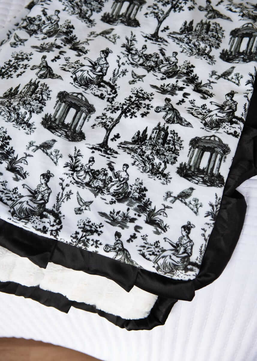 Toile black and white patterned fabric with classical design on a white background.