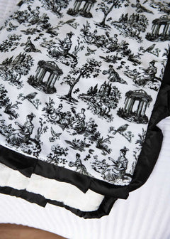 Toile black and white patterned fabric with classical design on a white background.