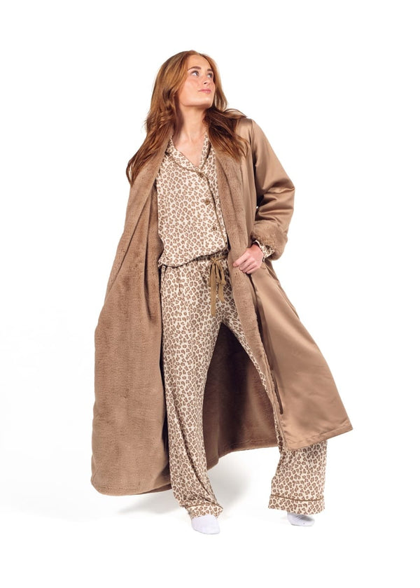 A woman modeling a long brown robe over a beige and brown animal print pajama set, standing against a solid white background.