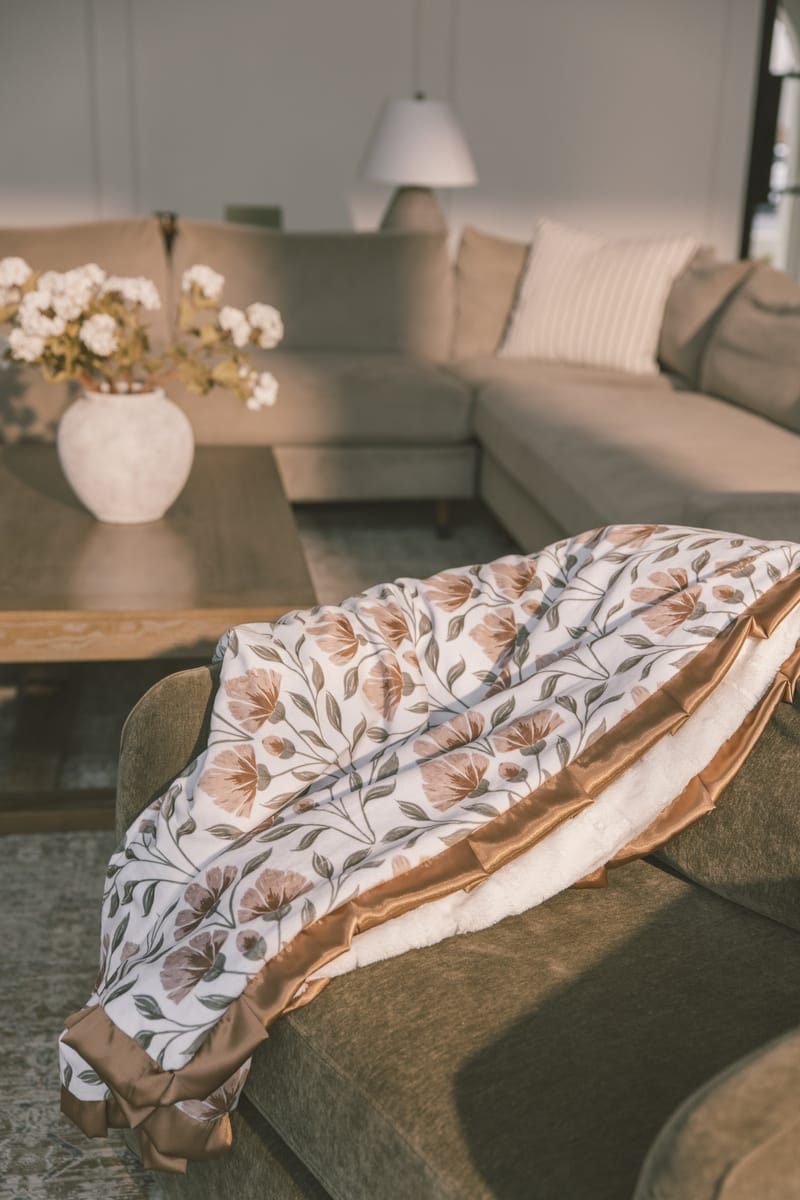 Cozy living room featuring the Flower Garden Blanket draped over a sofa with floral print and plush backing.