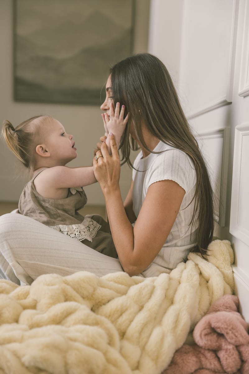 Woman and child sitting on soft yellow Hugs Honey Butter Blanket.