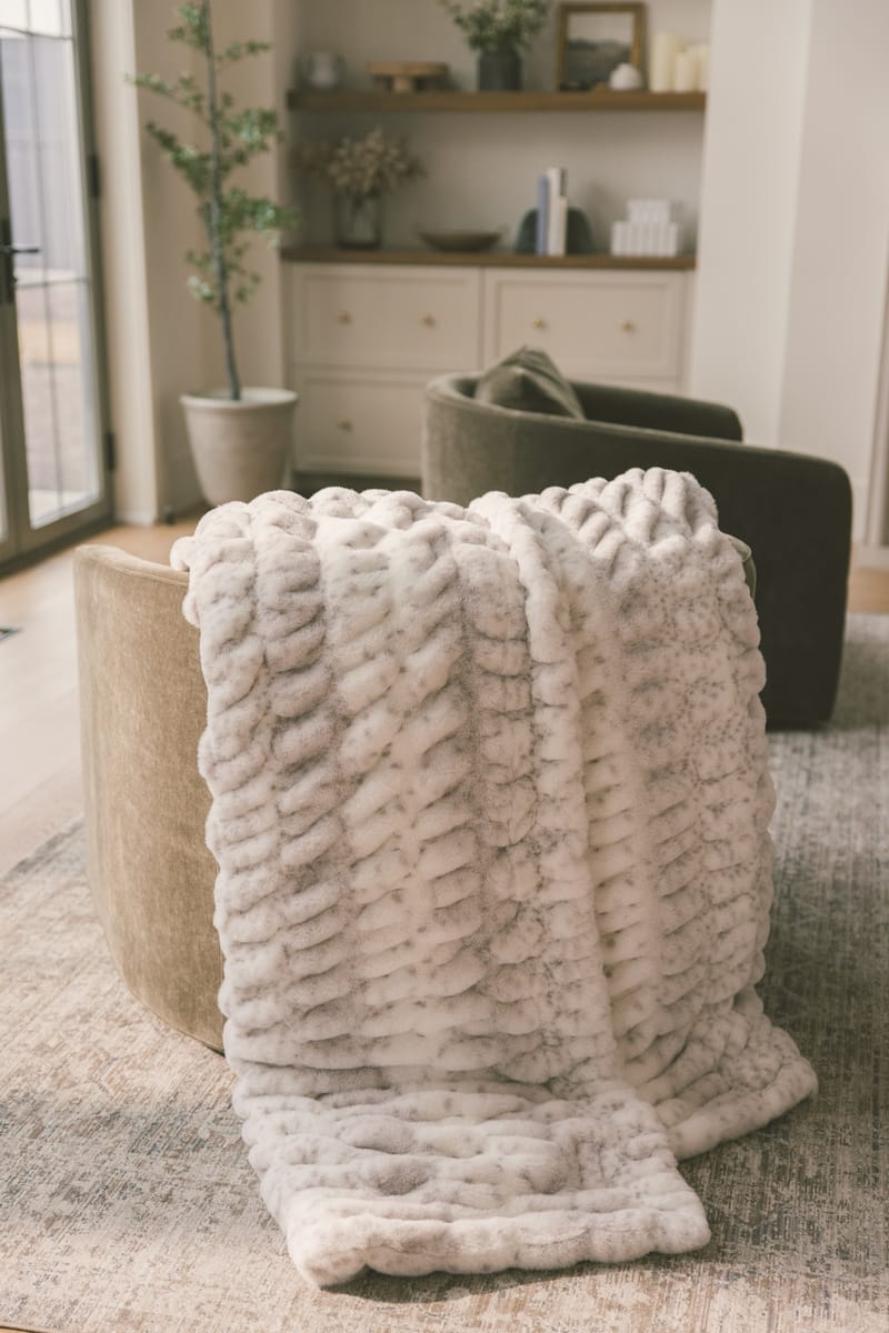 Hugs Cream Fawn Blanket draped over a cozy chair, showcasing its soft texture and fawn-inspired print.