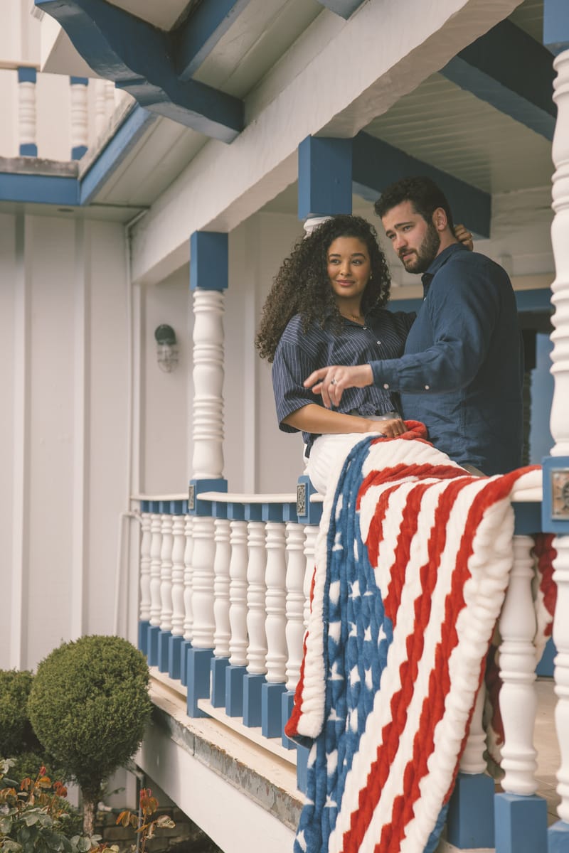 Two people on a porch with an American flag blanket