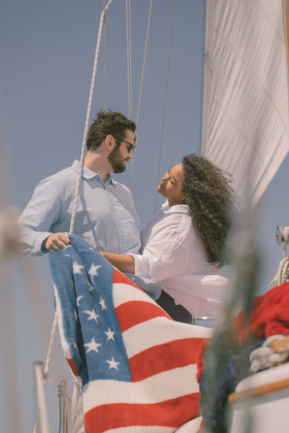 Two people on a sailboat with an American flag blanket