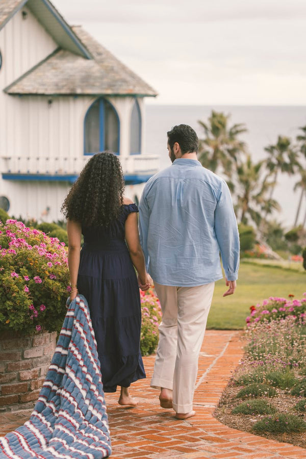 Couple walking hand in hand on a brick path with a blanket.