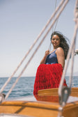 Woman on a sailboat with a red Minky Couture blanket, ocean and sky in the background