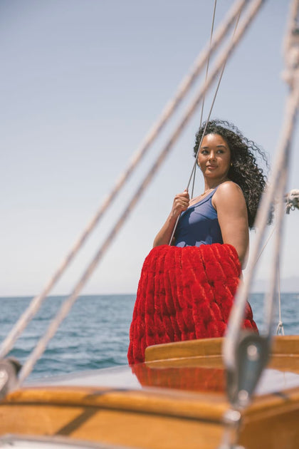 Woman on a sailboat with a red Minky Couture blanket, ocean and sky in the background