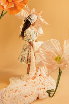 Girl in a floral dress surrounded by large flowers carrying a Minky Couture orange blanket