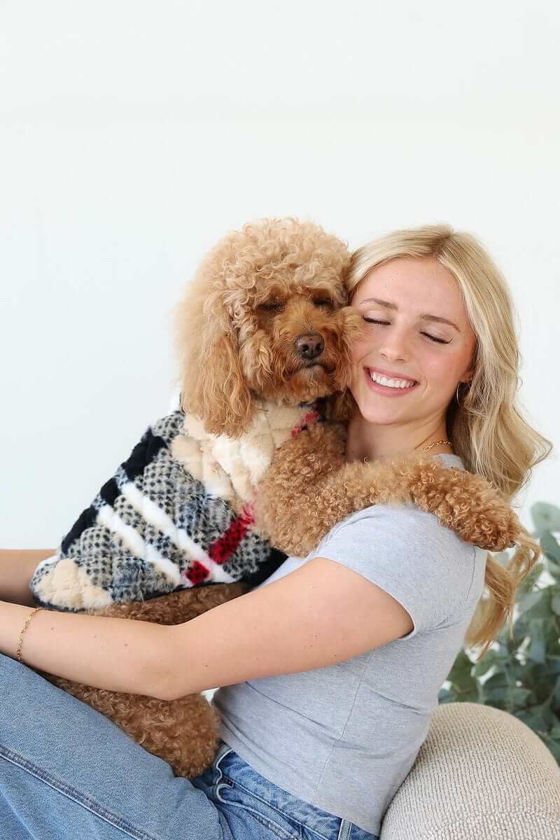 City Plaid/Cream Pet Vest on a dog being cuddled by a woman, showcasing comfort and style.