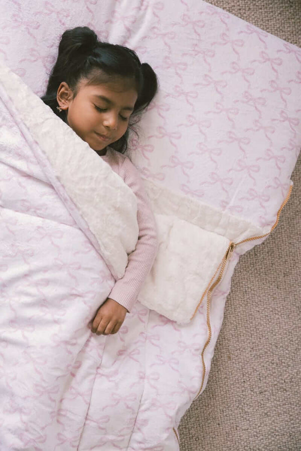 Minky Couture Sleeping Bag Pretty Pink Bows with a girl sleeping comfortably and cozy with a plush pillow.