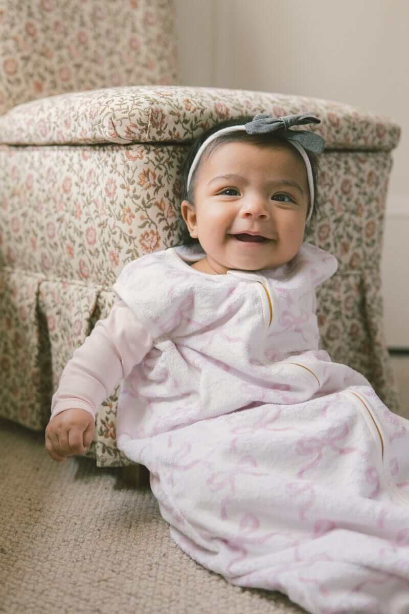 Baby smiling while wearing Pretty Pink Bows Wearable Minky Blanket, showcasing comfort and safety.